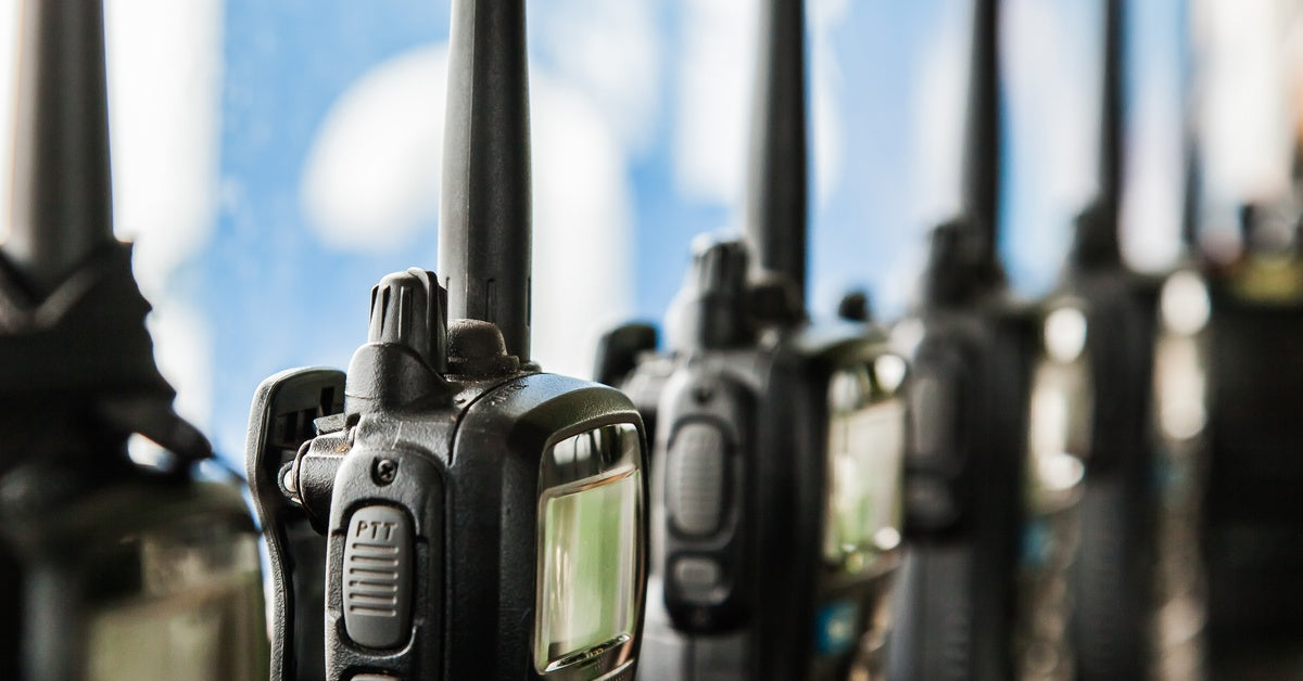 Black two-way radios sit in individual charging stations. They're lined up and charging side by side.