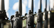 Black two-way radios sit in individual charging stations. They're lined up and charging side by side.